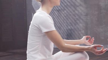 Genç kadın şık, minimalist bir ortamda meditasyon yapıyor. Sağlık, yoga ve rahatlama kavramı.