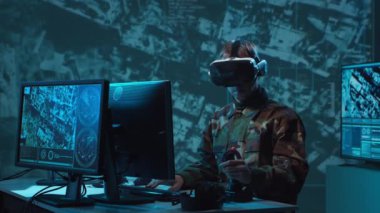 Bir askerin loş bir askeri kontrol odasındaki dramatik sahnesi, yoğun bir şekilde birden fazla bilgisayar ekranına odaklanmış, çok önemli operasyonel verileri gösteriyor..