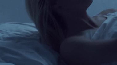 Genç bir kadın geceleri yatakta uzanıyor ve uykusuzluk hastalığına yakalanıyor. Güzel sarışın, uyuyan kız. Yatak odasında alacakaranlık, pencereden ay ışığı. Uykusuzluk, sağlık ve dinlenme konsepti. Ev