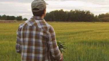 Farmer in front of a sunset agricultural landscape. Man in a countryside field. The concept of country life, food production, farming and country lifestyle.