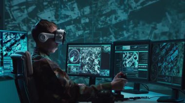 Bir askerin loş bir askeri kontrol odasındaki dramatik sahnesi, yoğun bir şekilde birden fazla bilgisayar ekranına odaklanmış, çok önemli operasyonel verileri gösteriyor..