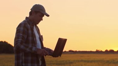 Farmer in front of a sunset agricultural landscape. Man in a countryside field. The concept of country life, food production, farming and country lifestyle.