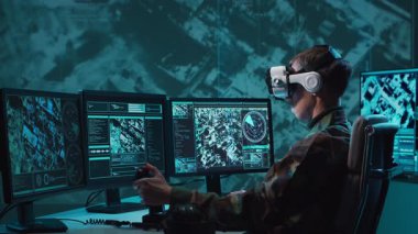 Bir askerin loş bir askeri kontrol odasındaki dramatik sahnesi, yoğun bir şekilde birden fazla bilgisayar ekranına odaklanmış, çok önemli operasyonel verileri gösteriyor..