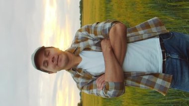 Günbatımı tarımının önündeki çiftçi. Kırsal kesimde bir adam. Kır hayatı, gıda üretimi, tarım ve kırsal yaşam tarzı kavramı.