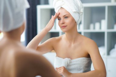 Genç Kız, Tuvalette Makyaj Aynası 'nın önünde oturuyor ve cilt kremi sürüyor. Güzel kadın kozmetik yenileme prosedürleri uyguluyor. Sağlık ve Güzellik Konsepti.