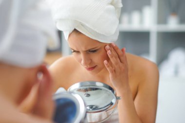 Genç Kız, Tuvalette Makyaj Aynası 'nın önünde oturuyor ve cilt kremi sürüyor. Güzel kadın kozmetik yenileme prosedürleri uyguluyor. Sağlık ve Güzellik Konsepti.