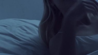 Genç bir kadın geceleri yatakta uzanıyor ve uykusuzluk hastalığına yakalanıyor. Güzel sarışın, uyuyan kız. Yatak odasında alacakaranlık, pencereden ay ışığı. Uykusuzluk, sağlık ve dinlenme konsepti. Ev