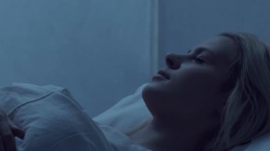 Genç bir kadın geceleri yatakta uzanıyor ve uykusuzluk hastalığına yakalanıyor. Güzel sarışın, uyuyan kız. Yatak odasında alacakaranlık, pencereden ay ışığı. Uykusuzluk, sağlık ve dinlenme konsepti. Ev