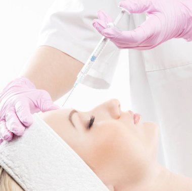 Güzel bir kadın yüzüne beyaz bir iğne vuruluyor.