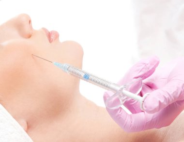 Güzel bir kadın yüzüne beyaz bir iğne vuruluyor.