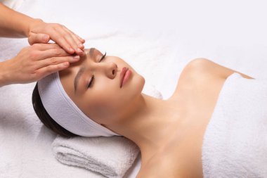 Sağlıklı genç bir kadın beyaz arka planda masaj yaptırıyor. Spa, sağlık ve dinlenme konsepti.