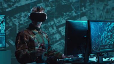 Bir askerin loş bir askeri kontrol odasındaki dramatik sahnesi, yoğun bir şekilde birden fazla bilgisayar ekranına odaklanmış, çok önemli operasyonel verileri gösteriyor..