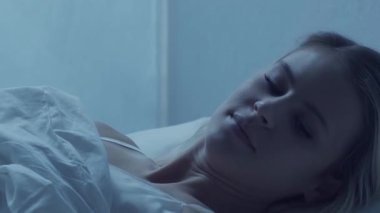 Genç bir kadın geceleri yatakta uzanıyor ve uykusuzluk hastalığına yakalanıyor. Güzel sarışın, uyuyan kız. Yatak odasında alacakaranlık, pencereden ay ışığı. Uykusuzluk, sağlık ve dinlenme konsepti. Ev