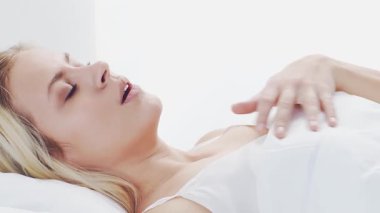 Huzurlu, huzurlu bir sahne. Genç bir kadın, rahat bir şekilde yatakta uyuyor. Yumuşak, doğal ışıklandırmayla. Rahatlama, dinlenme ve sükunet temaları için mükemmel. Ev kavramı.