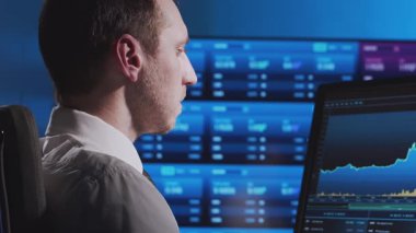 Tüccar, çalışma istasyonu ve analiz teknolojisi kullanarak ofiste çalışıyor. Profesyonel şifreleme simsarının işyeri. Yakın plan portre. Küresel finans piyasaları, iş stratejisi, döviz kurları ve bankacılık kavramları.