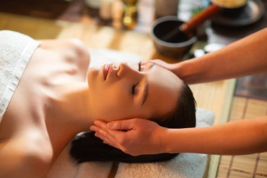 Genç, sağlıklı bir kadın egzotik geçmişiyle masaj yaptırıyor. Spa, sağlık ve dinlenme konsepti.