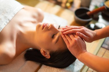 Genç, sağlıklı bir kadın egzotik geçmişiyle masaj yaptırıyor. Spa, sağlık ve dinlenme konsepti.