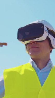 İnşaat alanının önünde duran profesyonel müteahhit. Kasklı ve yelekli ustabaşı. Ofis binası ve vinç arka planı. İş, gayrimenkul ve yatırım kavramları.