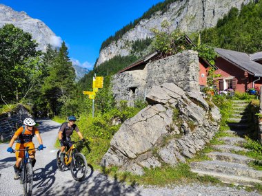 Engelberg, İsviçre - 16 Ağustos 2024: İsviçre Alplerinde Engelberg üzerinde bir çiftlik evinin önünde dağ bisikletçileri