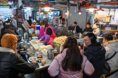 Seul, Güney Kore - 16 Ocak 2025: Güney Kore 'deki bir Seul pazarında yemek yiyen insanlar