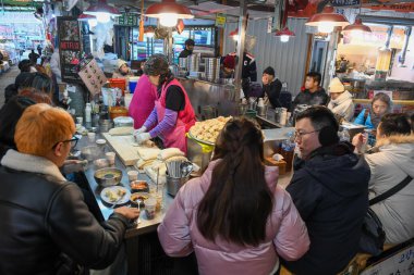 Seul, Güney Kore - 16 Ocak 2025: Güney Kore 'deki bir Seul pazarında yemek yiyen insanlar