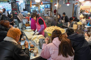 Seul, Güney Kore - 16 Ocak 2025: Güney Kore 'deki bir Seul pazarında yemek yiyen insanlar