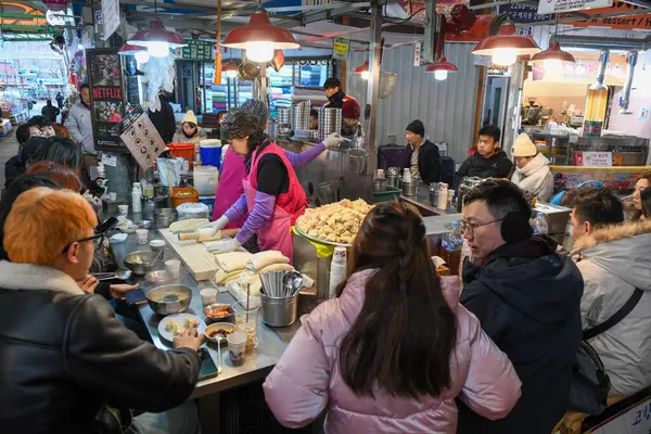 Seul, Güney Kore - 16 Ocak 2025: Güney Kore 'deki bir Seul pazarında yemek yiyen insanlar