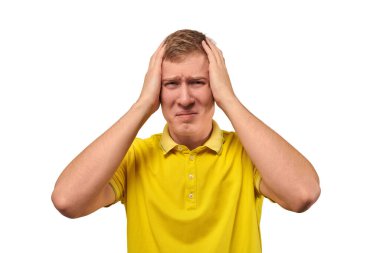Upset man in yellow T-shirt clutched at his head, forgetful man with headache isolated on white background. Young guy worried and frustrated, grabbed his head, sharp severe headache