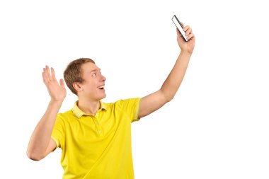 Funny guy in bright yellow T-shirt talking and video chatting using video translation with smartphone isolated on white background. Phone with white screen mockup. Funny young man taking selfie