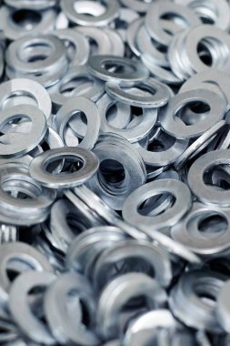 Bunch of stainless steel galvanized flat washers for fastener screws, nuts or bolts, hardware background. Stack of flat washers for distribute load of threaded fastener, close up