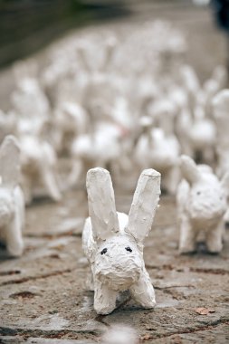 White rabbit statues from plaster close up, outdoor art exhibition, artificial white hares on city street. White decorative bunnies, toy rabbits, Easter urban decor concept