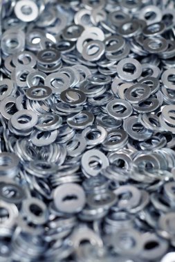 Bunch of stainless steel galvanized flat washers for fastener screws, nuts or bolts, hardware background. Stack of flat washers for distribute load of threaded fastener, close up