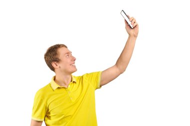 Funny guy in bright yellow T-shirt talking and video chatting using video translation with smartphone isolated on white background. Phone with white screen mockup. Funny young man taking selfie