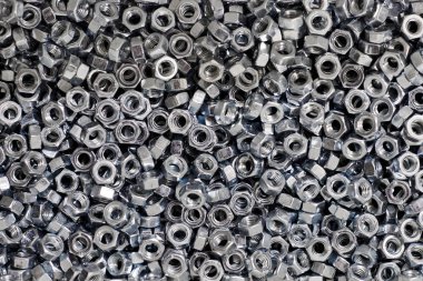 Bunch of galvanized hexagon nuts for bolts for fasten multiple parts together, hardware fasteners. Many high-quality stainless steel nuts, industrial close up background