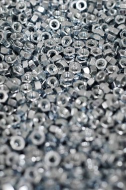 Bunch of galvanized hexagon nuts for bolts for fasten multiple parts together, hardware fasteners. Many high-quality stainless steel nuts, industrial close up background