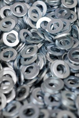 Bunch of stainless steel galvanized flat washers for fastener screws, nuts or bolts, hardware background. Stack of flat washers for distribute load of threaded fastener