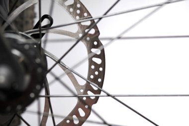 Hydraulic bicycle disk brakes, grey metal disc attached to bike wheel close up, effective popular mountain bicycle brakes. Hydraulic disk brakes on bicycle wheel, bicycle spokes gray background