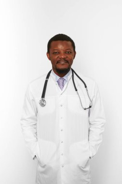 Smiling black bearded doctor man in white coat with stethoscope isolated on white background. Friendly adult black african american physician therapist portrait, pleasant candid male emotion