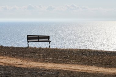 Empty bench on cliff before sea background, peaceful and quiet place for thinking alone, loneliness and loss of loved one concept. Pacifying view of marine horizon of Azov sea in Russia, copy space