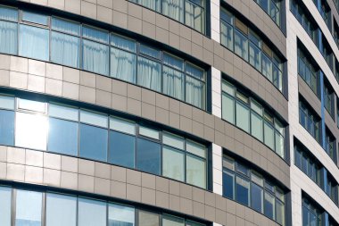 Close up view to office skyscraper windows, high business building windows with sunlight glare. Multistory still glass building with open space office premises for rent