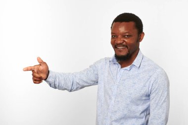 Happy african american black man with pointing finger in casual bright shirt isolated on white background. Smiling adult black guy portrait with pointing finger to left half size, candid male emotion