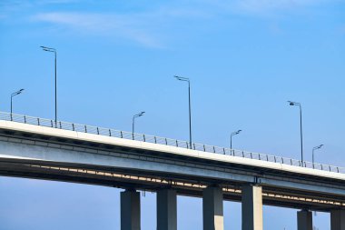 Concrete bridge in Rostov-on-Don city over river Don, Voroshilovsky bridge for cars on concrete supports with street lampposts. Russian bridge over deep fast river, blue sky background