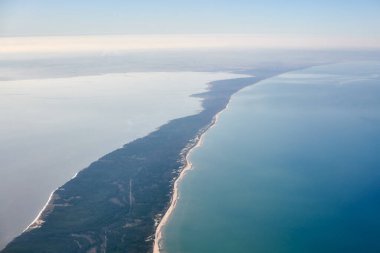 Aerial view from airplane window to Curonian spit in Kaliningrad Oblast, Russia, beautiful green forest and sandy beach on curved sand dune spit between Baltic sea. Aerial view to Kurshskaya kosa