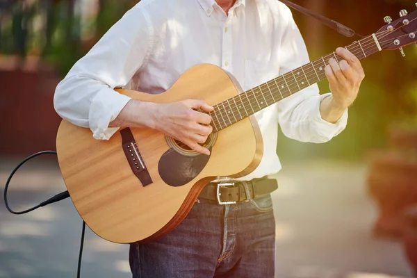 Man playing electro acoustic guitar at outdoor event, free musical performance of street musician. Right handed guitar player man playing six string electric acoustic guitar, very nimble fingers