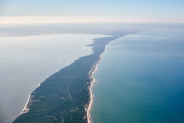 Aerial view from airplane window to Curonian spit in Kaliningrad Oblast, Russia, beautiful green forest and sandy beach on curved sand dune spit between Baltic sea. Aerial view to Kurshskaya kosa