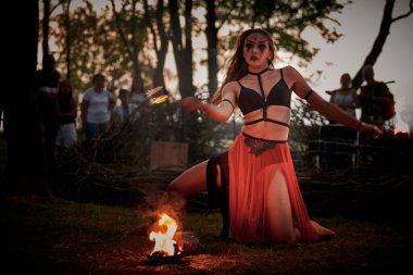 Açık hava sanat festivalinde kız ateş dansı gösterisi, akvaryumlu kadın ateş gösterisi sanatçılarının düzgün hareketleri. Alevli dans eden kadın sanat performansı, alacakaranlık ormanı arka planı