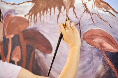 Ressam kız elinde boya fırçası ve açık hava resim festivalinde beyaz tuval üzerine soyut gerçeküstü manzara çiziyor, resim resim süreci. Kadın sanatçı atmosferik gerçeküstü resim çiziyor.