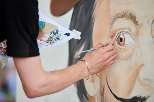 stock image Young man artist draws with paint brush surreal man portrait on white canvas at art painting festival, paintings art picture process. Woman paints Salvador Dali portrait, art of atmospheric surrealism