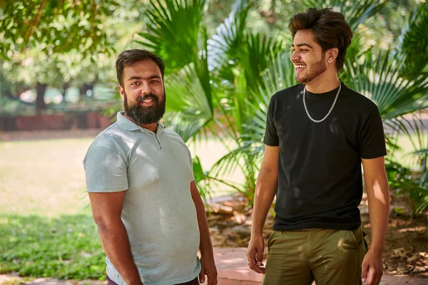 公園の緑のヤシの葉の背景には2人の面白いインド人男性が笑ってヒンディー語を話す 真の男性の友情 公園の屋外散歩で大声で笑っている二人の面白いインド人の男 — ストック写真