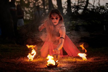 Açık hava sanat festivalinde kız ateş dansı gösterisi, akvaryumlu kadın ateş gösterisi sanatçılarının düzgün hareketleri. Alevli dans eden kadın sanat performansı, alacakaranlık ormanı arka planı